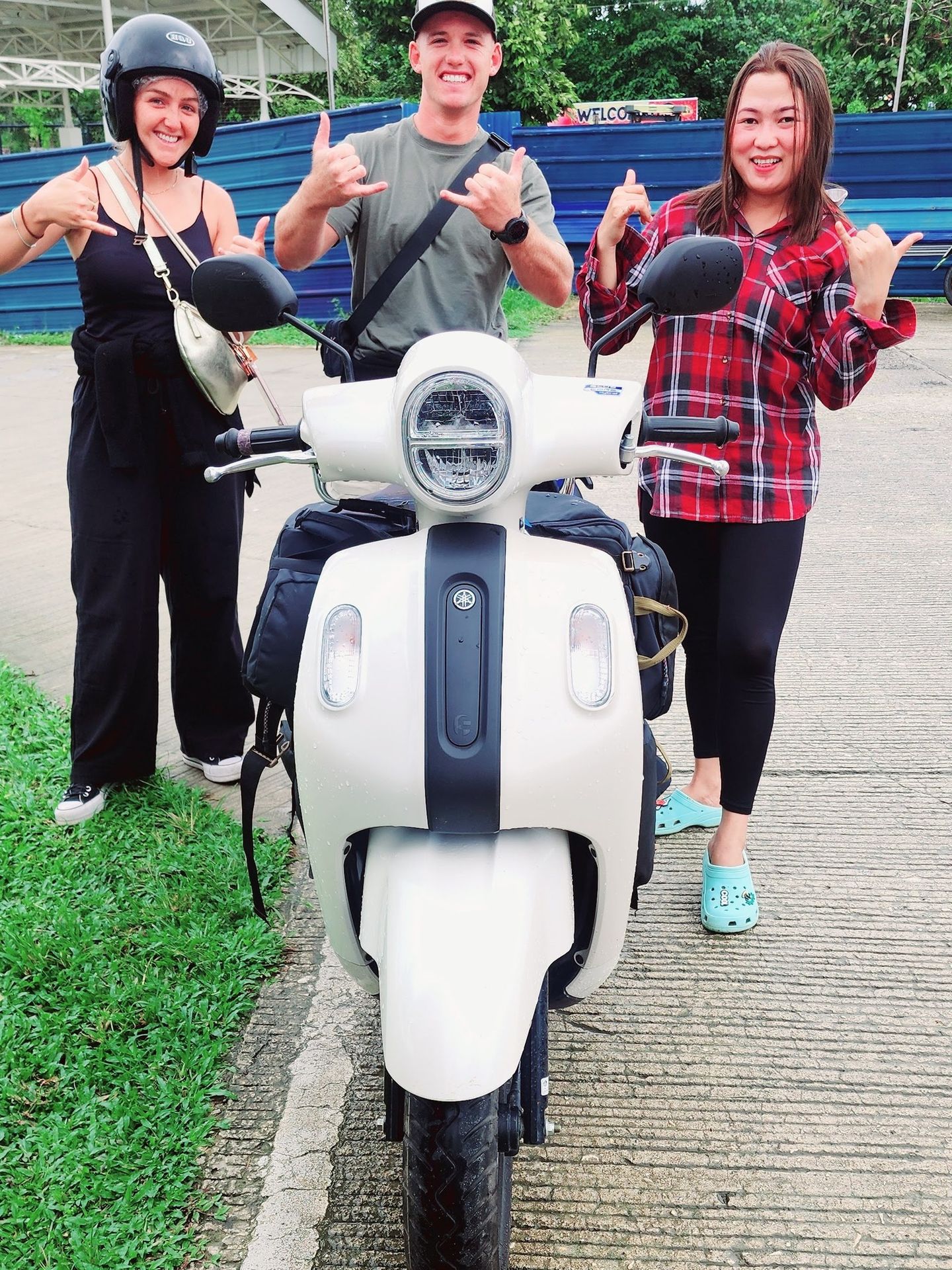 Cream Yamaha Fazzio seen front-on with three smiling people giving shakas