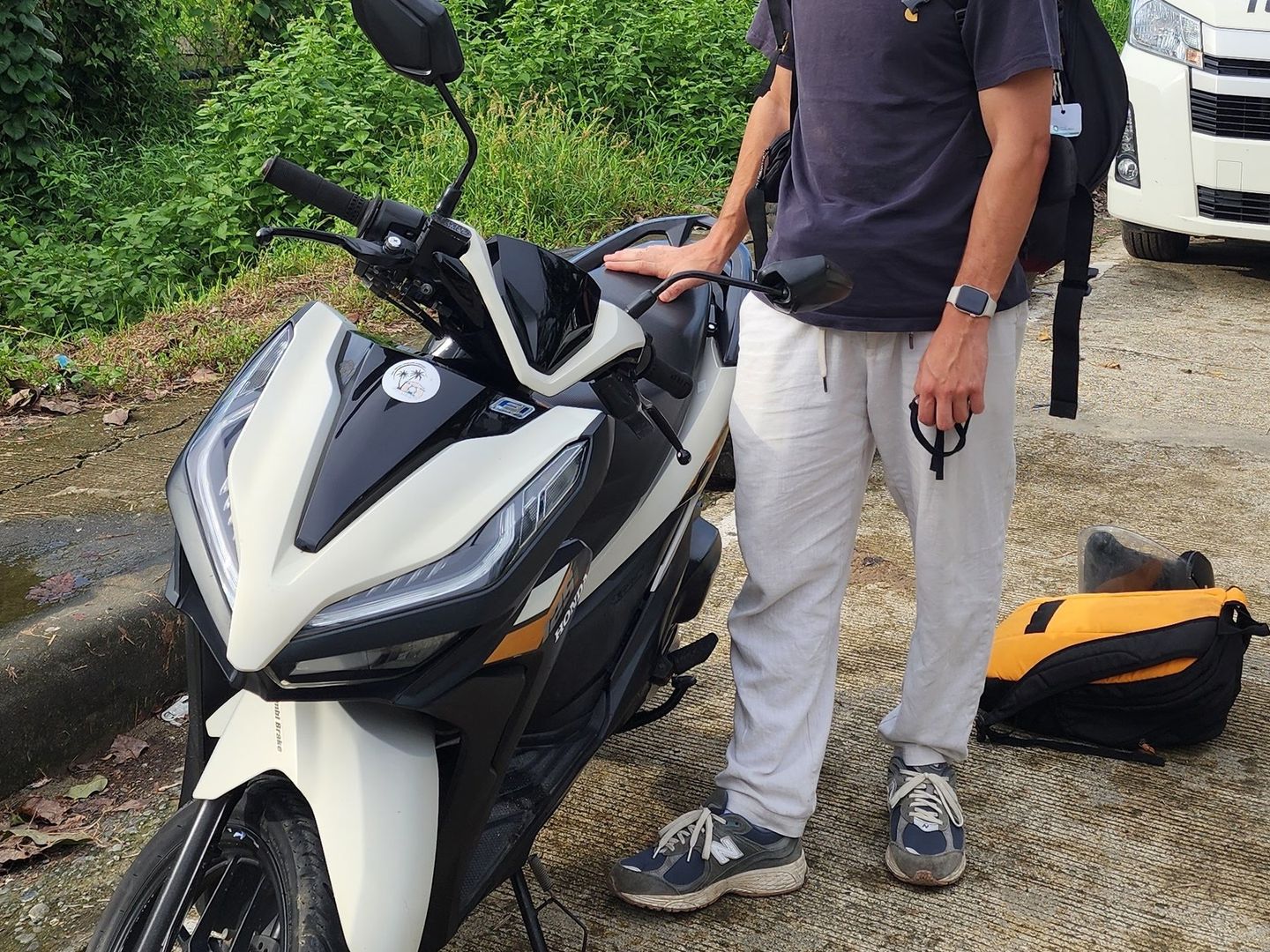White and black new-model Honda Click scooter with a traveller standing beside it